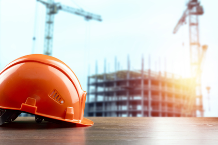 Orangeconstruction helmet close-up on the background of construction. The concept of architecture, construction, engineering, design. Copy space.の写真素材