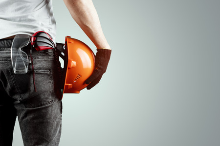 The builder, the architect holds in his hand a construction helmet on a light background, a tape measure. Concept architecture, construction, engineering, design, repair. Copy spaceの写真素材