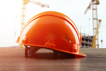 Orangeconstruction helmet close-up on the background of construction. The concept of architecture, construction, engineering, design. Copy space.の写真素材