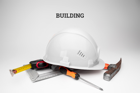 White construction helmet, tape measure, hammer, screwdriver on a light background. Inscription construction. Concept architecture, construction, engineering, design, repair.の写真素材