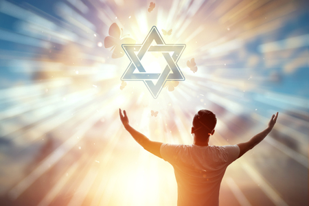 A man against the backdrop of the symbol of Judaism, a prayer, the star of David. The concept of hope, faith, religion, a symbol of hope and freedom.の写真素材