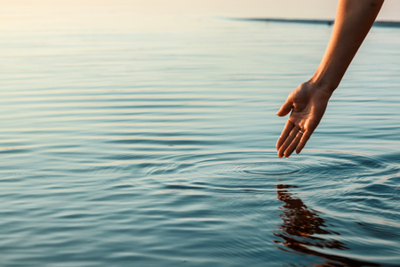 Woman's hand touching the water surfaceの写真素材