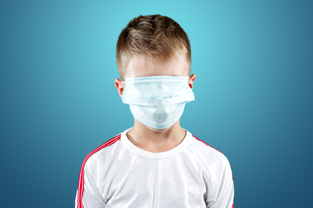 Little boy, a child in a medical mask on a blue background. The concept of an epidemic, influenza, protection from disease, vaccination.の写真素材