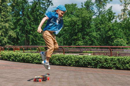 A small city boy and a skateboard. A young guy is riding in a park on a skateboard. City Style. City...