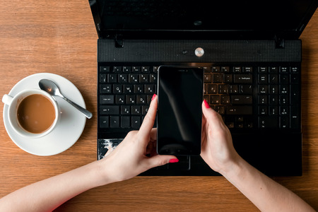 Female's hands with phone on laptop background. mockupの写真素材