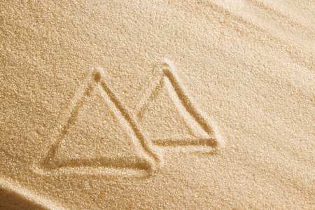 On the sand painted Egyptian pyramids, beach sand, drawing suggestive for the summer. Beach background. View from above. The concept of summer, summer vacations, recreation, holidays.の写真素材