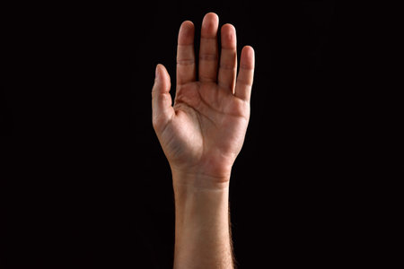 Male's palm raised up, isolated on a dark background. Isolate