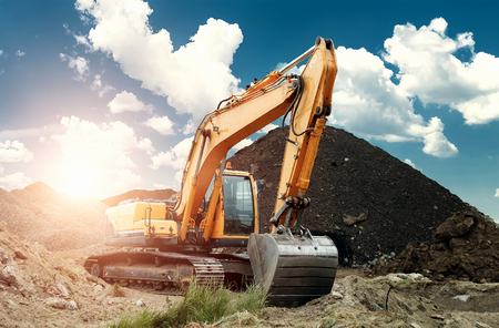 Excavator at the construction site, sand, crushed stone, against the blue sky background. Construction equipment, construction.の写真素材