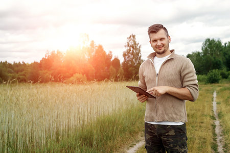 Man A farmer standing in the field and using a tablet. Modern application of technologies in...