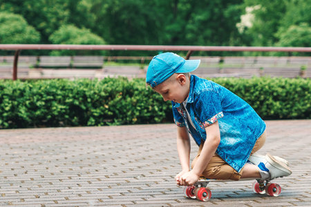 A small city boy and a skateboard. A young guy is riding in a park on a skateboard. City Style. City...