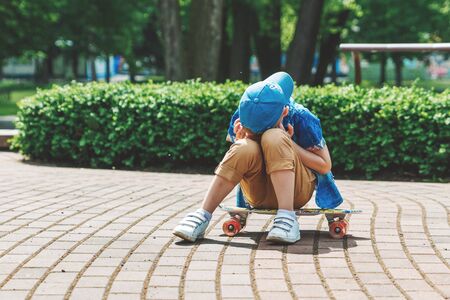 A small city boy and a skateboard. A young guy is riding in a park on a skateboard. City Style. City children. A child learns to ride a skateboardの写真素材