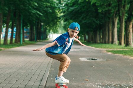 A small city boy and a skateboard. A young guy is riding in a park on a skateboard. City Style. City children. A child learns to ride a skateboardの写真素材