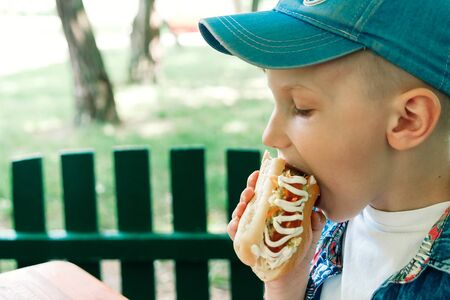 little caucasian boy eating burger, looking downの写真素材