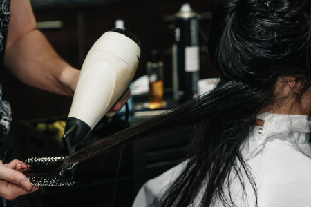 Drying long brown hair with hair dryer and round brush. Close-up.の写真素材