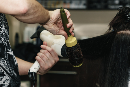 Drying long brown hair with hair dryer and round brush. Close-up.の写真素材