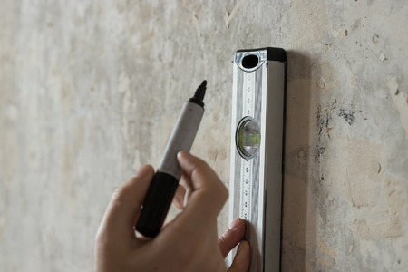 A man measures on the wall with a ruler, a tape measure, a level, marks the markers. The concept of construction work, repair with their own hands, finishing work.の写真素材