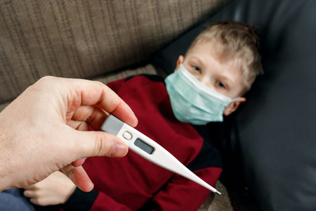 A father in the hands with a fever thermometer for a boy who has a fever. The concept of disease,...