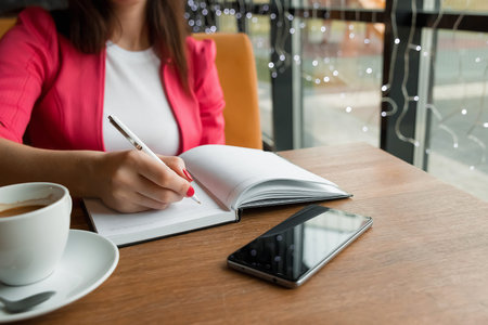 A young business woman is sitting in a cafe and then hanging in a diary. Lunch time, portrait of a...