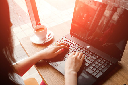 close-up office desk. Workspace with girl's hands, laptop, coffee cup. Business woman.