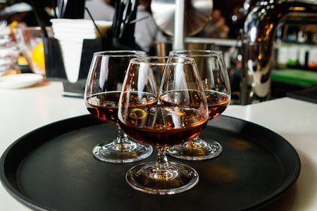 Three glasses with cognac on a dark tray, close-up, service, nightclub.の写真素材