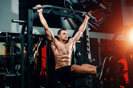 bodybuilder on the bar raises his legs up, exercises on the press in the gym. Great training of a...