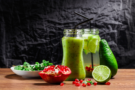 Refreshing drink from kiwi, green apple, lime, mint and pomegranate on a wooden table. The concept of a healthy diet, detox.の写真素材