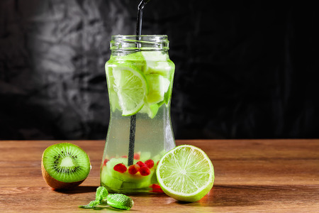 Refreshing drink from kiwi, green apple, lime, mint and pomegranate on a wooden table. The concept of a healthy diet, detox.の写真素材