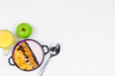 Morning breakfast. Spoon, bowl with homemade yogurt and cornflakes, raisins, almonds, green apple and orange juice on white background, top view, flat lay. Concept of healthy food, healthy food, detox. Copy Spaceの写真素材