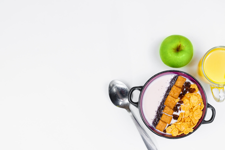 Morning breakfast. Spoon, bowl with homemade yogurt and cornflakes, raisins, almonds, green apple and orange juice on white background, top view, flat lay. Concept of healthy food, healthy food, detox. Copy Spaceの写真素材