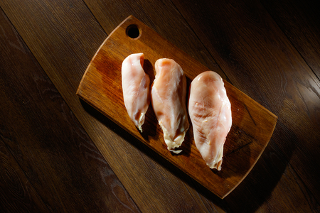 Raw, chicken fillet on a cutting board, a kitchen board, rosemary, pepper, salt, seasoning. The concept of a recipe for cooking chicken.の写真素材