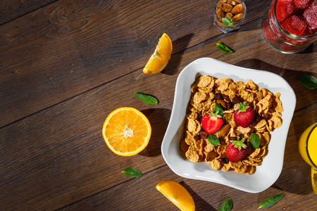 Cereal, morning breakfast, corn flakes, raisins, almonds, mint leaves, orange juice, strawberry, top view, on a dark wooden background, flat lay. The concept of healthy, proper nutrition, ditox.の写真素材