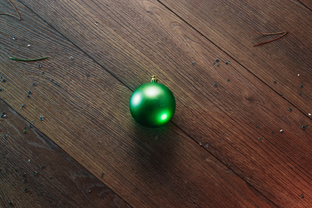 One green Christmas ball on a wooden background. Christmas and New Year. Copy space background. View from above.の写真素材