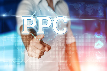 Businessman clicks on a virtual screen and selects "PPC". Blue background. Business concept. Mixed mediaの写真素材
