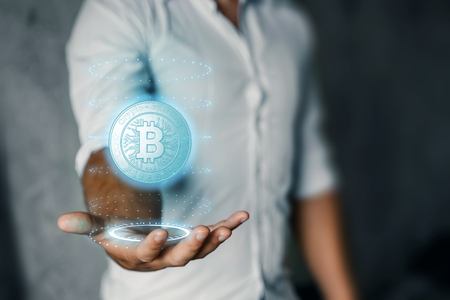 A businessman is holding a bitcoin icon, business, new technologies in his hand. The concept of crypto currency. Blockchain technology.の写真素材