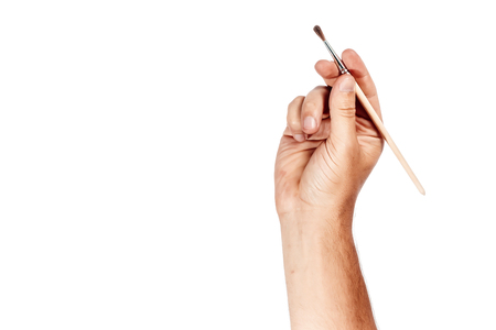 A man's hand holds a brush isolated on a white background.の写真素材