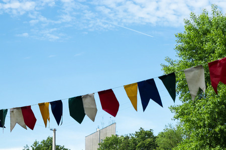 Fair flags blowing in the wind with blue skies and brick building in background.の写真素材