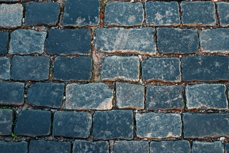 Cobbled stone road shown at a small angle, reflection of light seen on the roadの写真素材