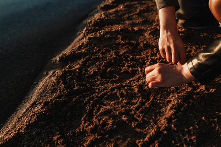 A loving couple draws a heart on the sand on the beachの写真素材