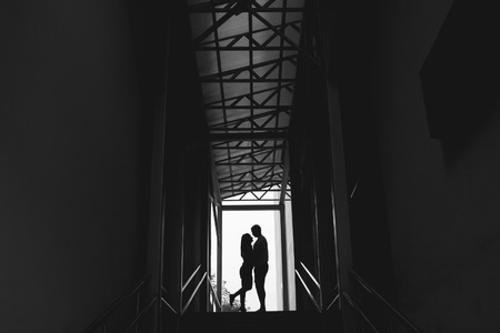 Silhouette of a couple on bright background at the end of an underground pedestrian tunnelの写真素材