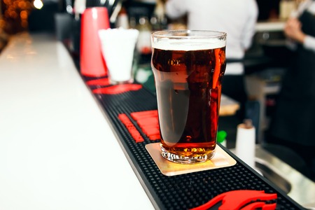 Dark beer in a glass on a white barの写真素材
