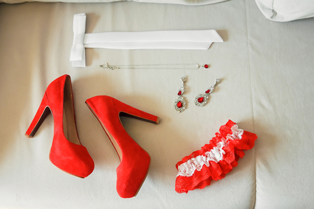 Red women's shoes stand on the windowsill, wedding, boutonniere.の写真素材