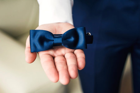 The groom holds a blue bow tie on his handの写真素材