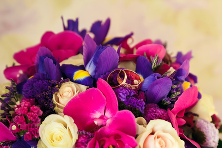 Golden wedding rings on the background of a wedding bouquet of red rosesの写真素材