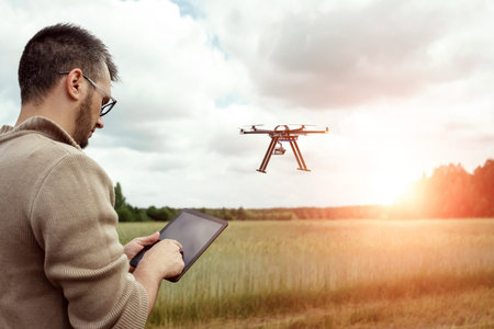 A male farmer manages a drone over agricultural land. Technology, innovation to increase...