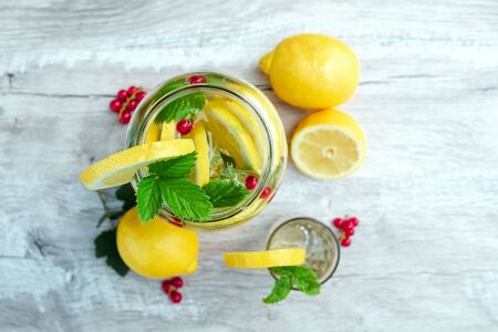 Homemade lemonade with fresh lemons, mint and cranberries. A can of lemonade on a white wooden background. The concept of fresh lemonade, cold juice, heat, summer coolness.の写真素材