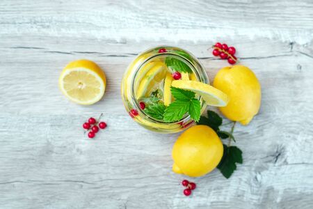 Homemade lemonade with fresh lemons, mint and cranberries. A can of lemonade on a white wooden background. The concept of fresh lemonade, cold juice, heat, summer coolness.の写真素材