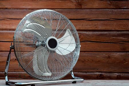 Large tabletop ventilator on the table against the background of a wooden wall. The concept of heat, hot weather, air conditioning.の写真素材