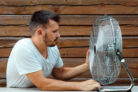 Sweaty man in front of a cooling ventilator, refreshing in the concept of hot summer. The concept of...