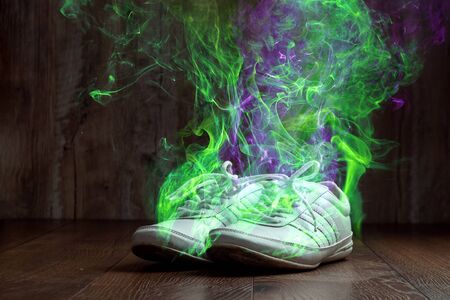 White sneakers closeup on a wooden background, stink. Nasty smell. Stink legs, fungus on the legs.の写真素材