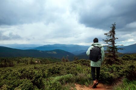 Creative background, A male tourist walks through a mountainous area with a backpack. The concept of active tourism, recreation, the Carpathians. Copy space.の写真素材